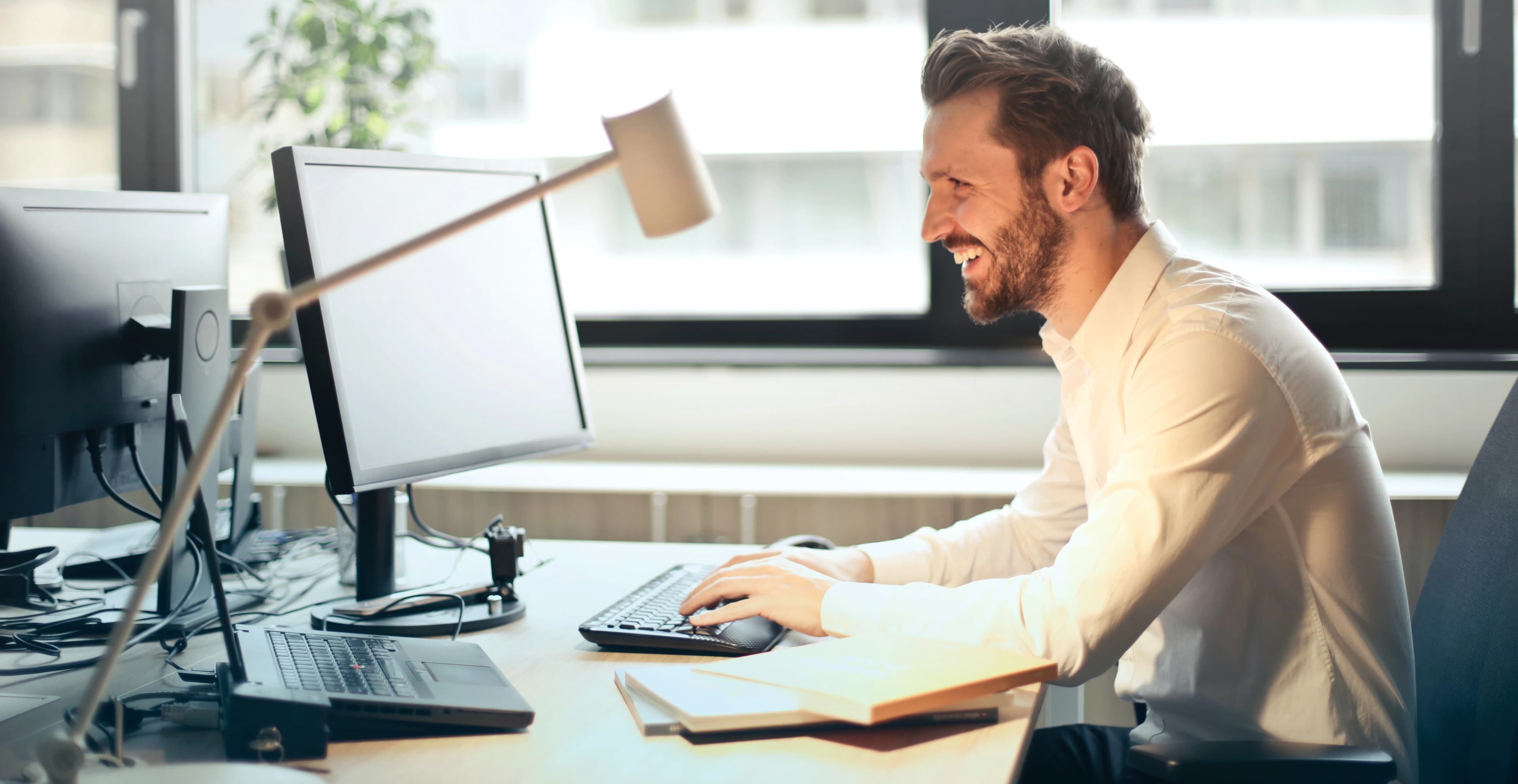 Man smiling and typing on computer